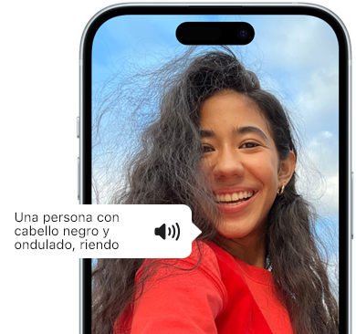 Un iPhone 15 muestra cómo la funcionalidad VoiceOver lee la descripción de una imagen: una persona con pelo negro ondulado sonriendo